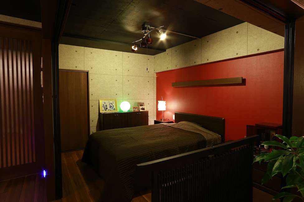 赤い壁とシーリングライトで引き締まる寝室