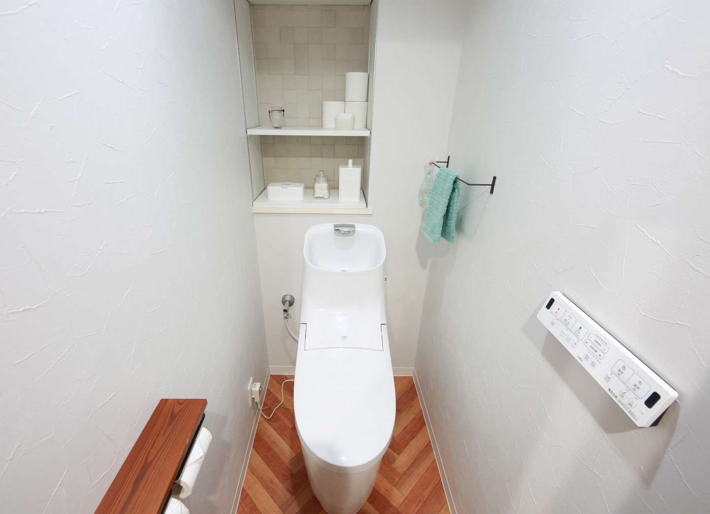 トイレのリフォーム。床材とトイレットペーパーホルダーはウッディにまどめ、シンプルな中にナチュラルで温かみのある印象に